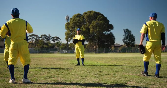 Warming up senior male players tossing and catching baseball with gloves on ballfield