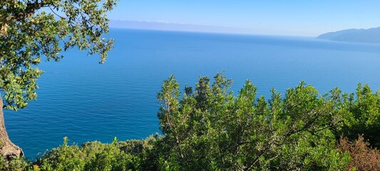Crystal clear sea with mountain backdrop and green landscape