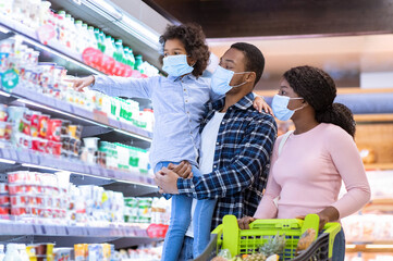 Shopping during covid-19 outbreak. Young black family wearing disposable masks while buying dairy...