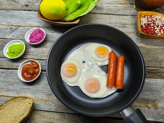 delicious appetizing breakfast of fried eggs and sausages on a frying pan