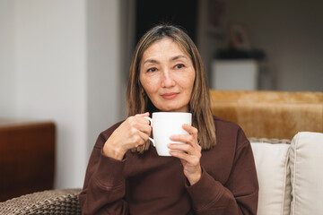 Woman enjoying a warm drink while seated in a cozy indoor setting during the afternoon, showcasing...