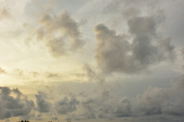 A wide, horizontal photo of a small, silhouetted boat with people in the middle of a calm river. The horizon is a dark line of trees, and the sky is filled with dark, textured clouds. A few small bird