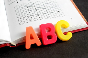 There is a math book with English letters on a black background.