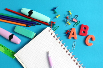 On a blue background there are school supplies and a checkered notebook.