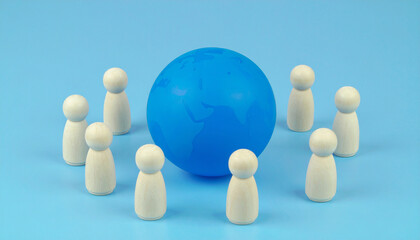 Obraz premium Miniature wooden team figures around abstract blue globe model, global collaboration concept.