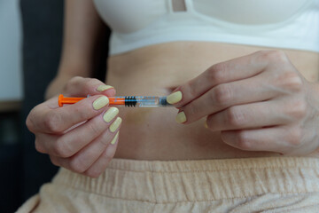A close-up of a person preparing to administer medication with a syringe, showcasing attention to personal health and self-care practices in a modern, comfortable setting.