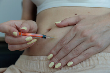 A Close-Up View of a Person Preparing to Inject Medication into Their Abdomen with a Syringe,...