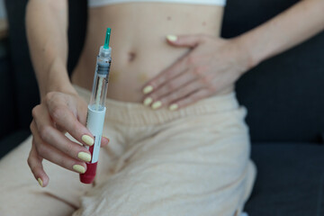 Close-Up of a Hand Holding a Medical Syringe Over a Bare Midsection, Highlighting the Connection...