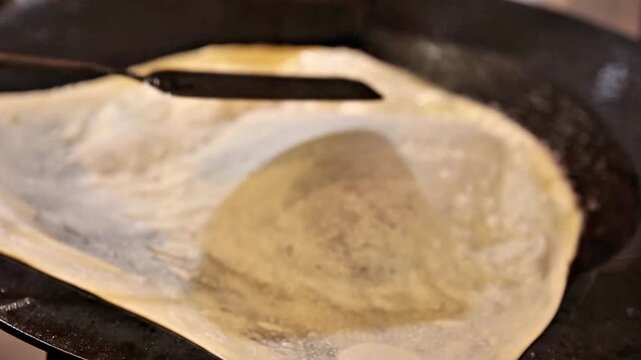 Traditional martabak telor cooking on hot pan, stuffed with egg, vegetables, and spices. Authentic Indonesian street food with crispy dough and savory filling, perfect for culinary content.
