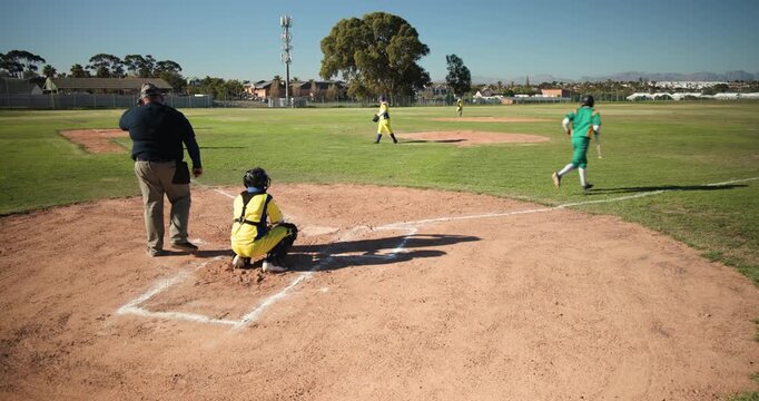 On dirt infield, pitcher is delivering pitch, batter is swinging bat and running toward first base