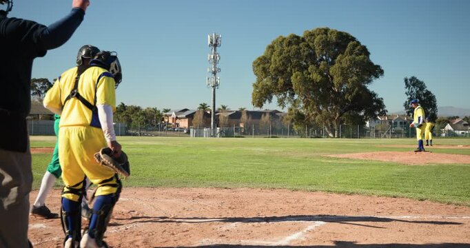 Pitcher winding up and delivering pitch on dirt infield, batter swinging, sprinting to reach base