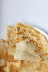 Traditional Russian and Estonian pancakes (blini) folded on a white plate. Perfect for stock photography focused on homemade food, Eastern European cuisine, breakfast concepts, or minimalist meals.