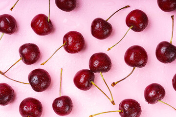 Close up of red raw fresh sweet cherries with water droplets on pink wet background. Macro view...