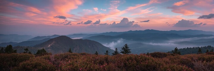 Obraz premium Mountain vista at sunset with colorful clouds and hazy valleys.