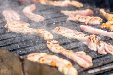Close up of Bacon Cooking on a Smoky BBQ
