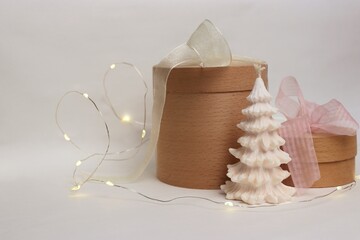 A natural festive composition with wooden gift boxes, a white Christmas tree-shaped candle, and a...