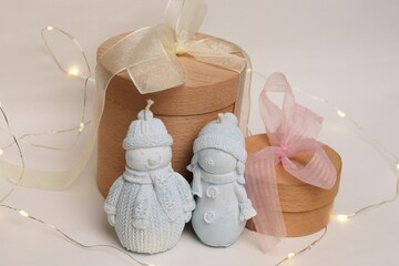 A winter composition featuring snowmen figurines, wooden gift boxes, and garlands—a charming...