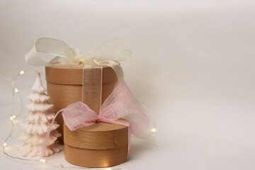 A festive composition with wooden gift boxes, a white Christmas tree-shaped candle, and a garland...