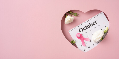 Symbolic representation of Breast Cancer Awareness Month with a pink ribbon, calendar displaying October, and delicate white flowers.