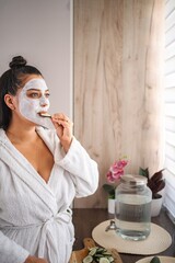 Woman enjoying a beauty treatment with a facial mask and cucumber slices