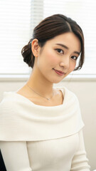白いニットを着て優しく微笑む日本人女性の顔のアップ
