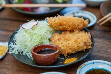 Fried seafood cutlet with shredded cabbage and dipping sauces on wooden table