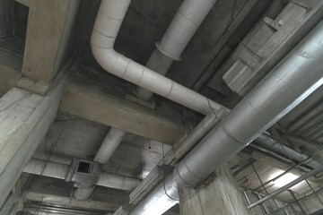 Obraz premium Industrial infrastructure pipes and ducts beneath a concrete structure.