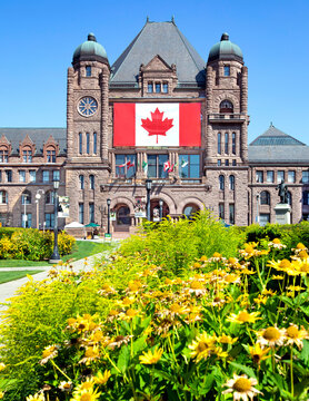 Ontario Legislative Building at Queen's Park with large Canadian flag and flowers in foreground