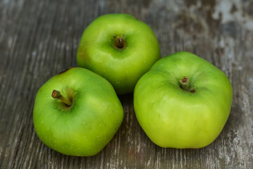Tree green fresh apples on rustic wooden table. Natural background. Health food concept.