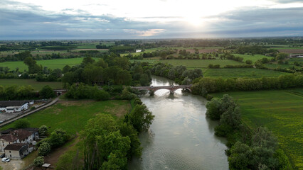 Aerial view of Pontevico BS Italy showcasing the Oglio River flowing under an ancient stone bridge...