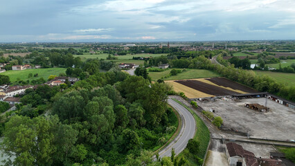 Scenic aerial drone view of Pontevico Brescia Italy showcasing lush green landscapes rolling hills and rural countryside under a cloudy sky presenting a picturesque Italian panorama