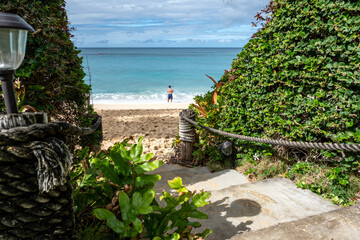 Pathway to sandy beach with fisherman at Kahana Bay, Oahu, Hawaii on January 28, 2023