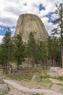 Devils Tower National Monument blue sky white clouds trees