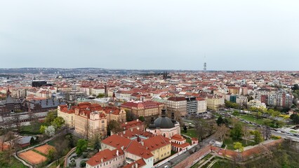 Fototapeta premium Aerial panorama of a historic European city with endless red rooftops, domed churches, and a modern tower rising above. Contrast of heritage architecture and urban development in one frame.