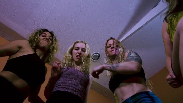 POV of four women stomping and kicking someone