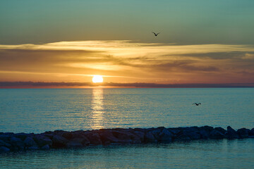 Serene sunset over tranquil sea with flying birds.