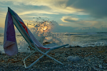 Beach chair at sunset with ocean waves.