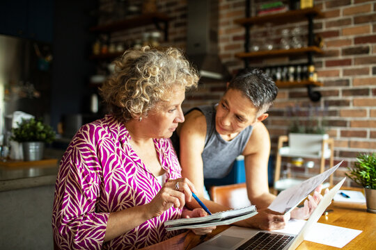 Senior lesbian couple discussing finances at home with laptop