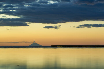 Sunset over sea with distant volcano.