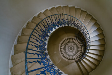 the iconic Tulip Stairs located in the Queen's House, a historic building in Greenwich, The handrail is adorned with decorative floral motifs, wrought iron structure was the first geometric.
