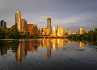 Fototapeta premium Tallest building in Texas over Lady Bird Lake in the city skyline of Austin TX in summer 2025 as the sun casts a golden light