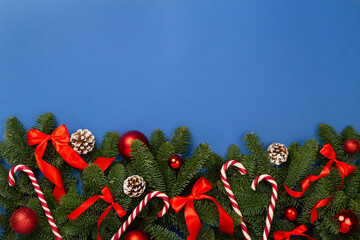 Christmas tree branches with festive decoration on color background, top view