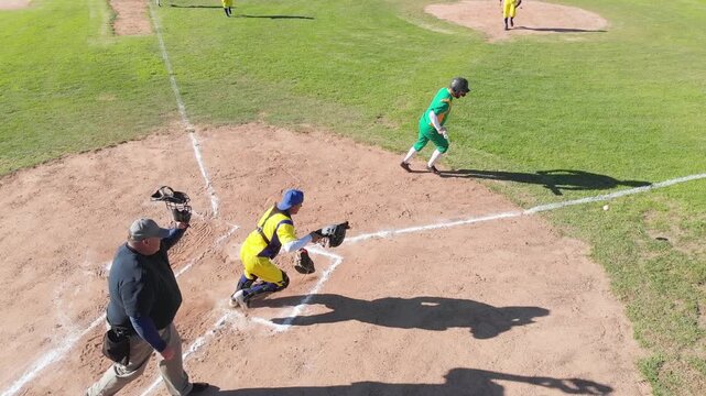On pitch batter batting at home plate racing 1st catcher chasing ball, next batter getting ready