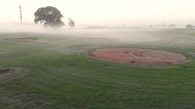 Camera is panning right across foggy clay infield after opening shot, revealing additional diamonds