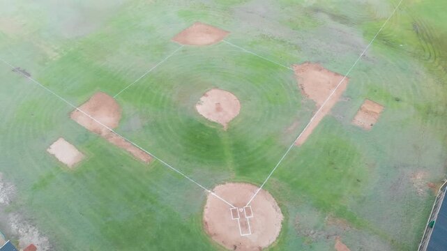 Drone opening shot drifting forward and panning across baseball diamond, revealing pitcher's mound