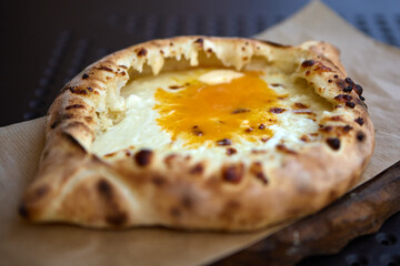 Traditional Georgian khachapuri with egg and cheese filling on wooden board