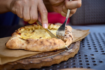Hand holding a slice of Georgian khachapuri with cheese