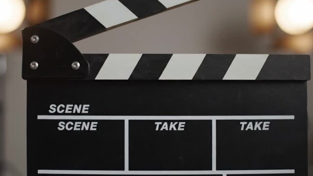 Cinematic close-up of a clapperboard snapping shut in slow motion, bright studio lighting.