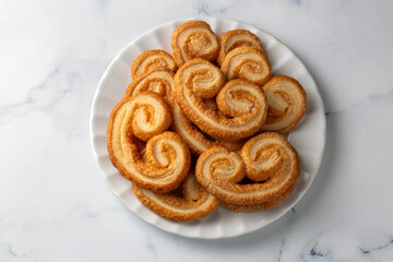 Golden palmier puff pastry cookies with caramelized layers on a white background, perfect for bakery branding or food visuals.