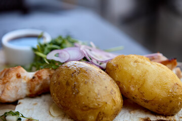 Boiled potatoes served with grilled chicken skewers